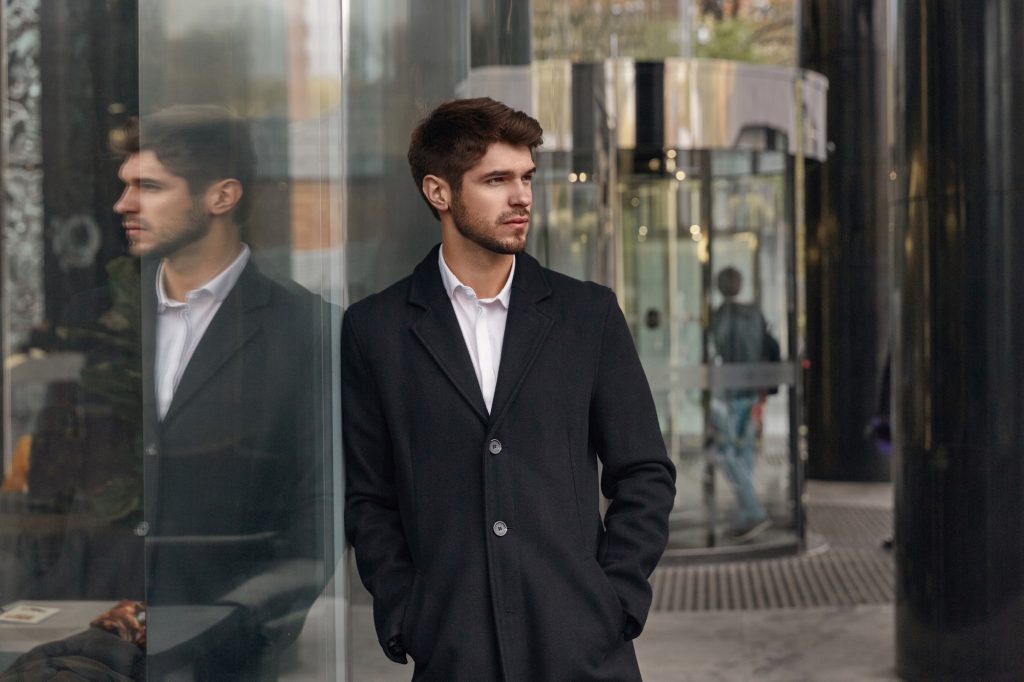 Serious business man standing by glass building