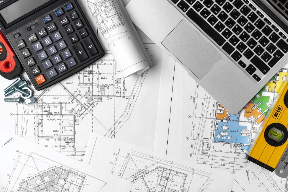 Working table of interior designer with blueprint and laptop
