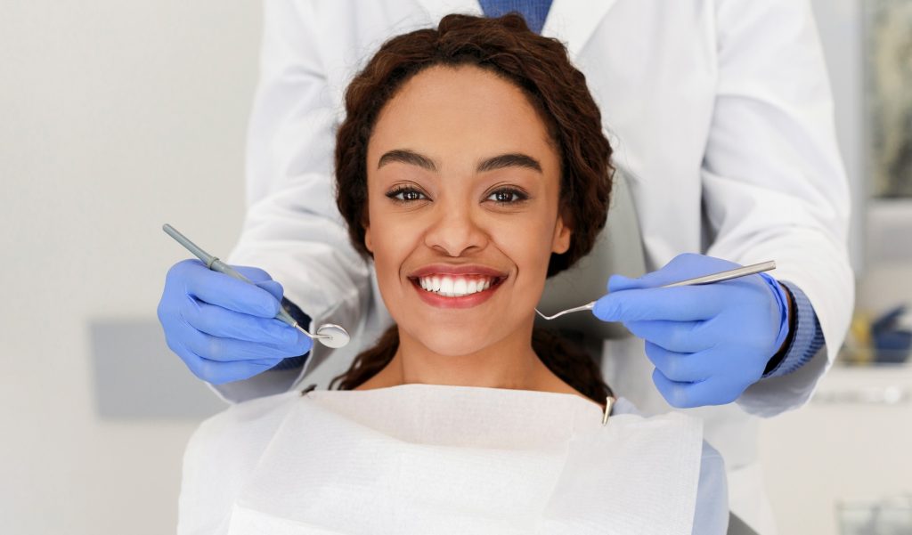 Cheerful african woman and dentist staying behind