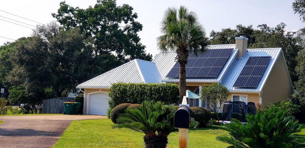 Beach house with solar panels on rooftop for energy surrounded by palm trees for tropical vibes.