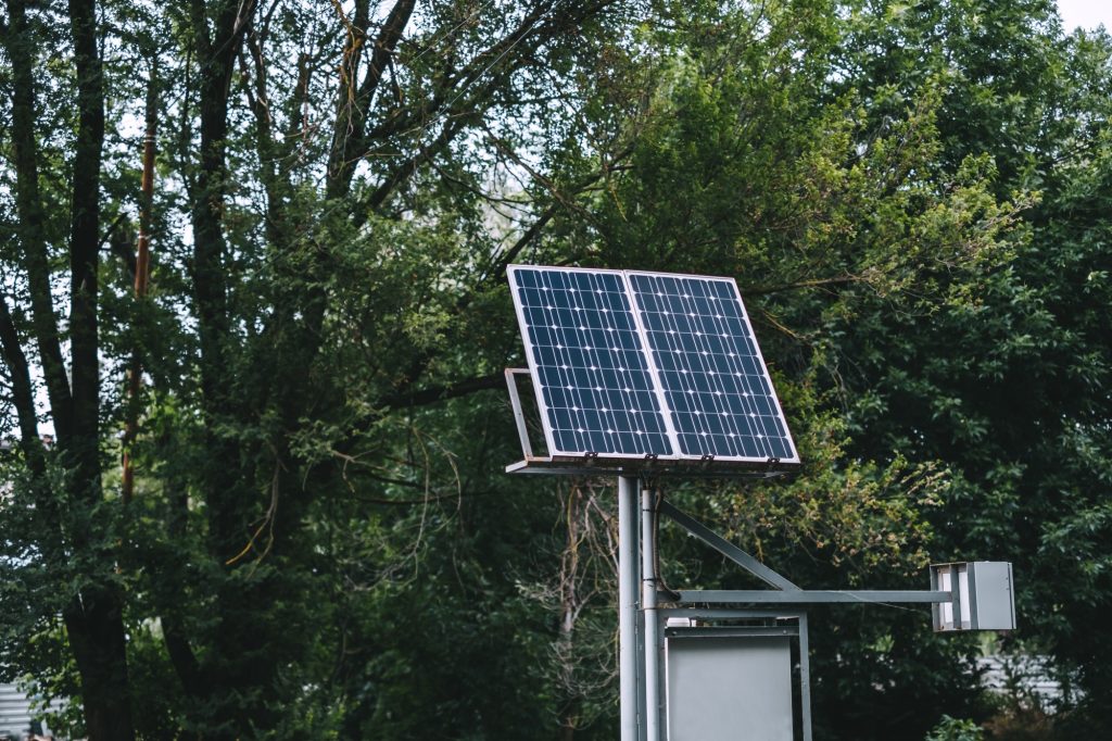 Solar battery panel in the city park near the trees.
