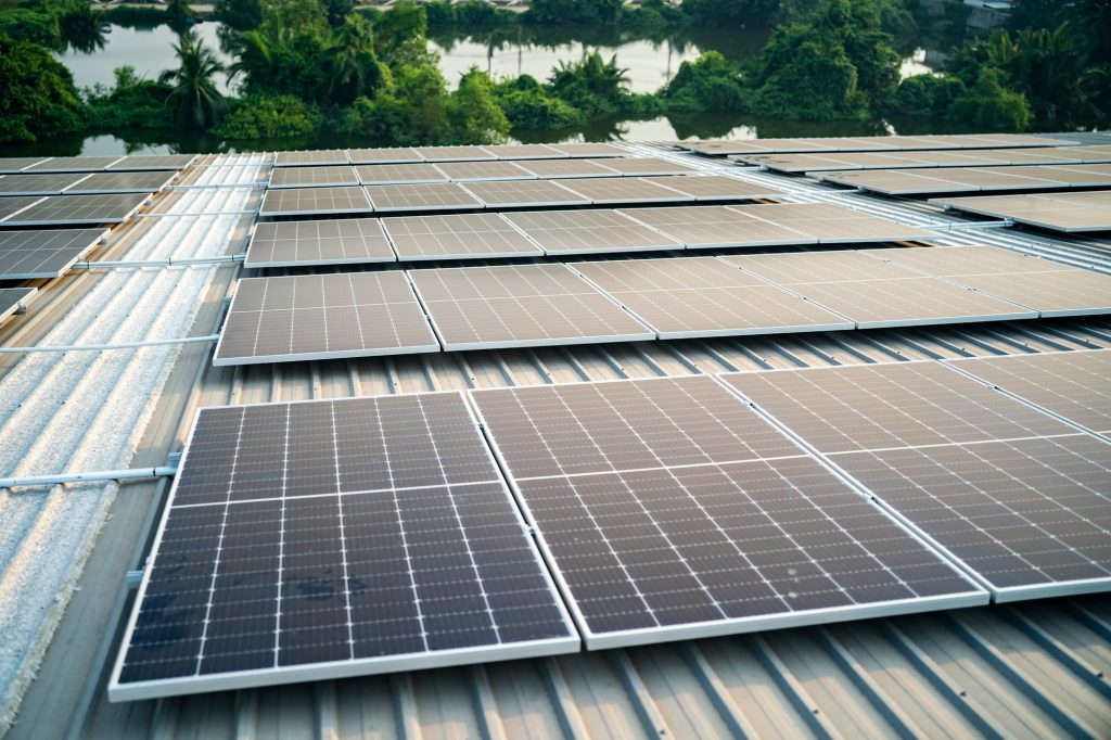 Solar panel installer installing solar panels on roof of warehouse