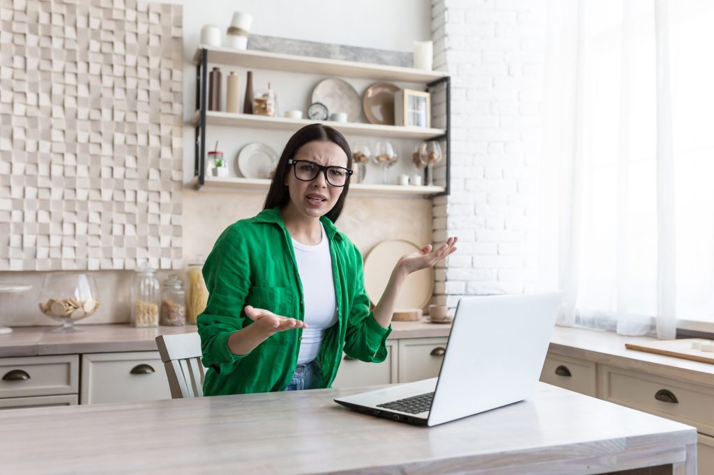 Freelance. Work at home. Confused woman,sitting at a table with a laptop, received bad news, upset