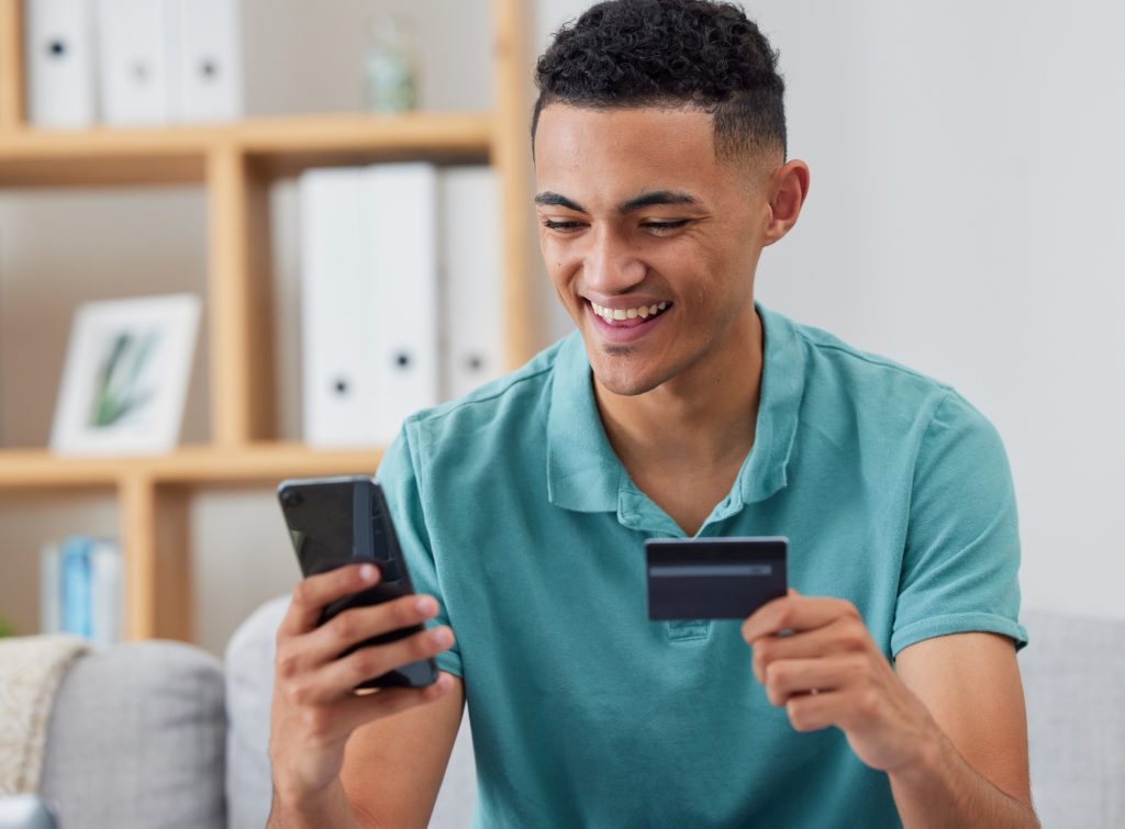 Happy man, credit card and smartphone, online shopping and fintech with payment and discount on sto
