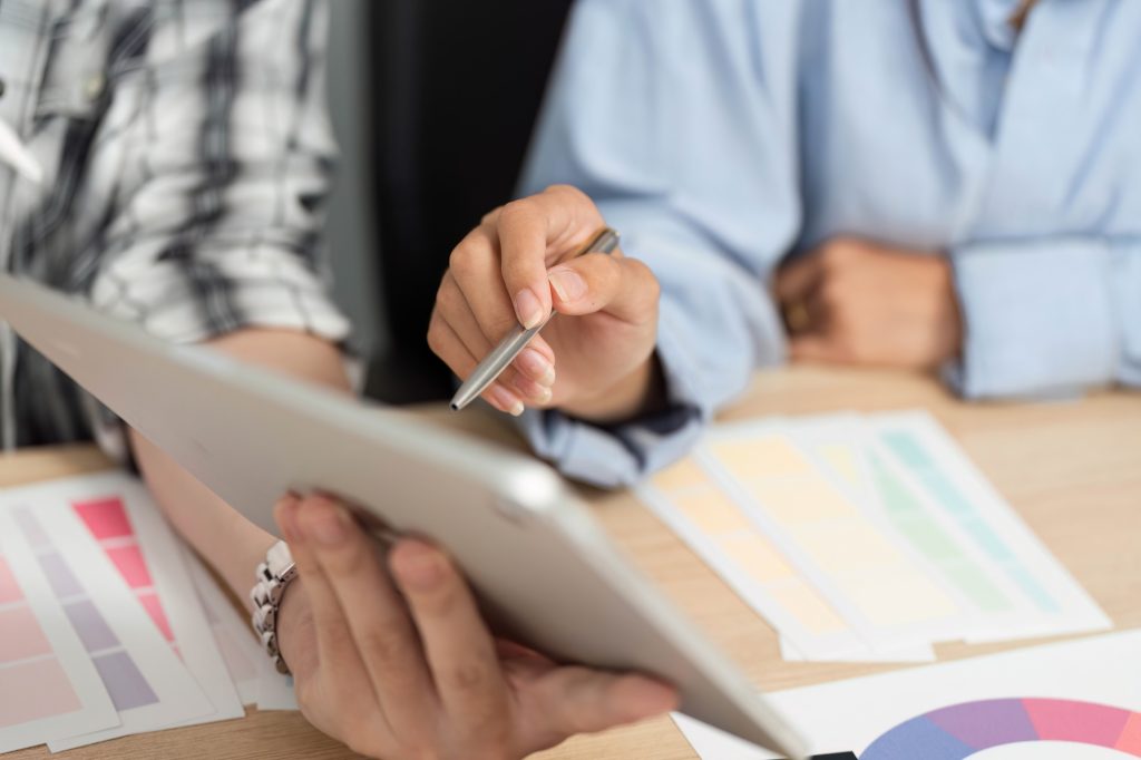 UX and UI Design Tools. Hands holding a tablet while discussing design options.