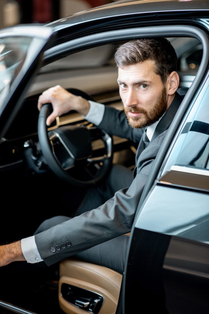Businessman in the luxury car at the showroom