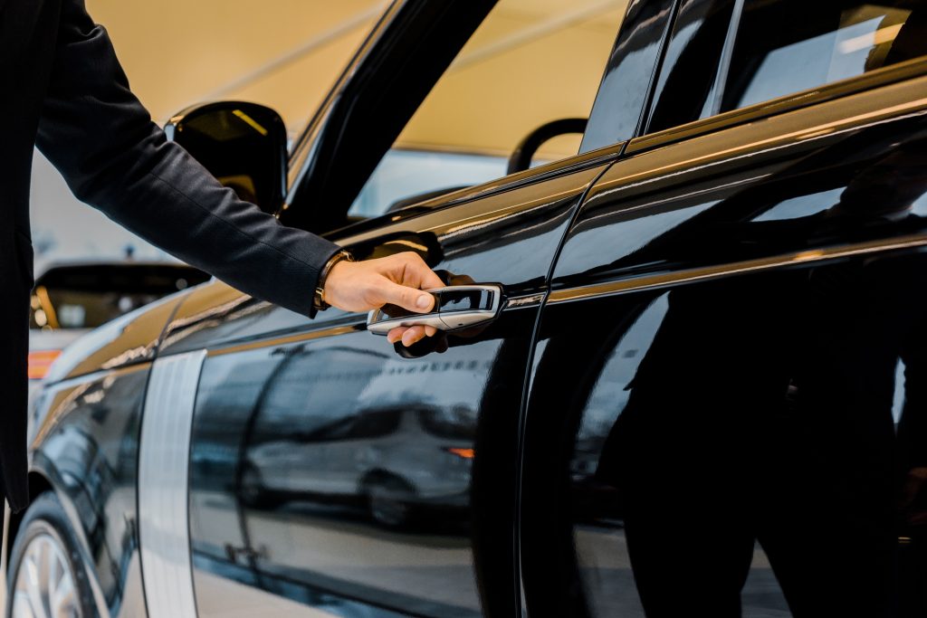 cropped image of businessman in suit opening door of black automobile