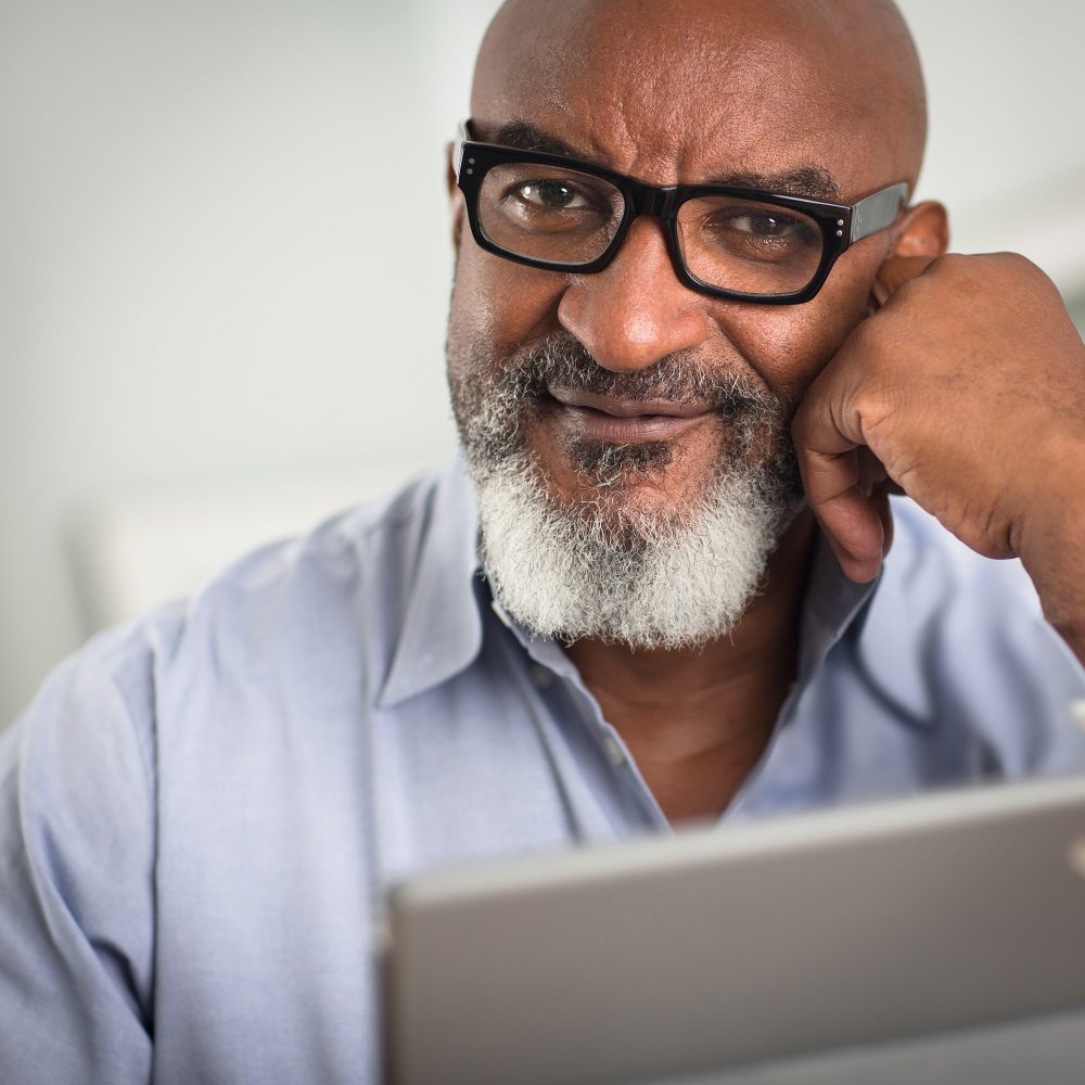 Portrait of mature man with greying beard and glasses, looking at camera smiling