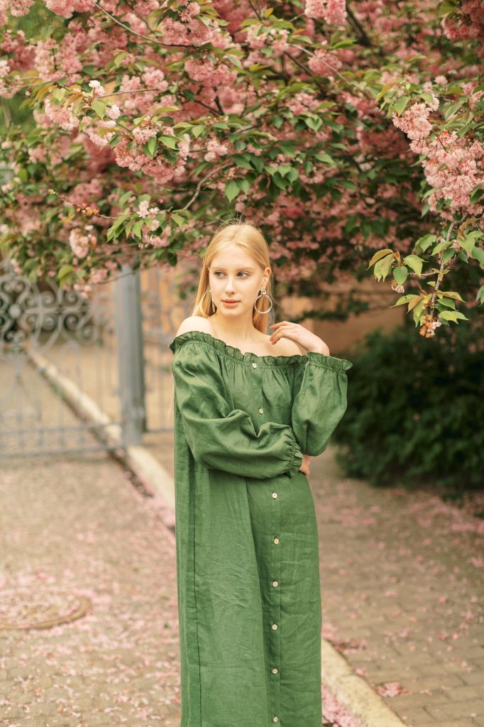 Sensual blond girl in pink linen dress walking in park.