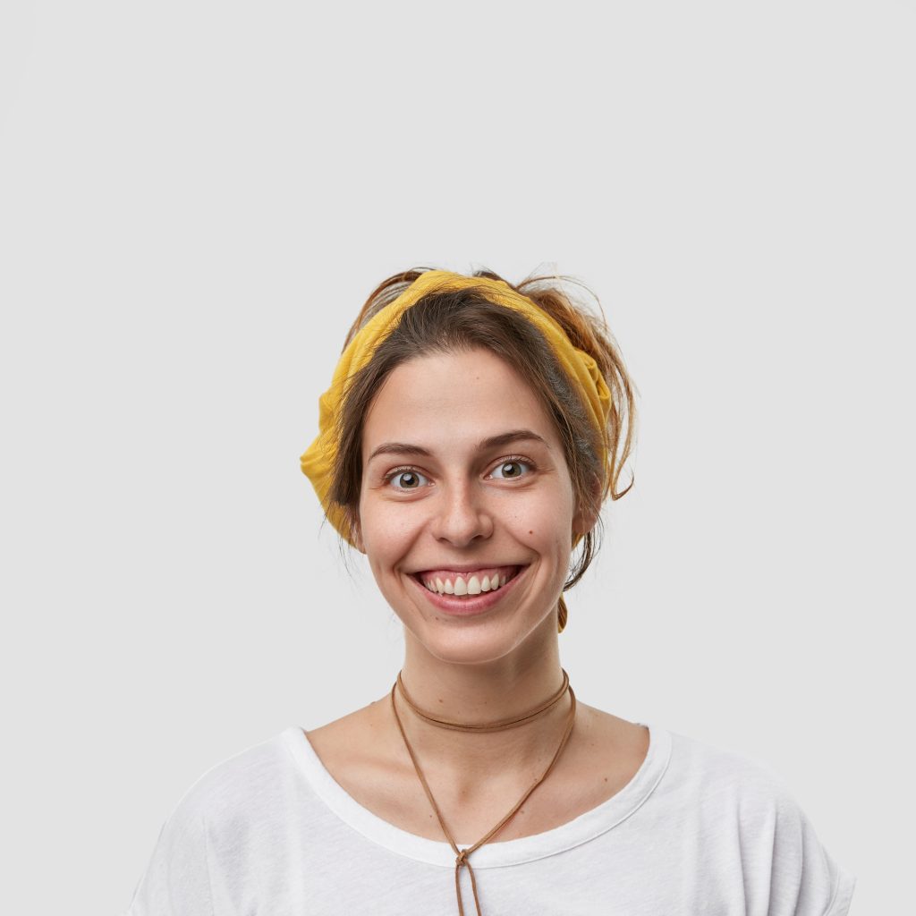Vertical shot of cute pleasant looking woman with cheerful expression, looks happily directly at cam